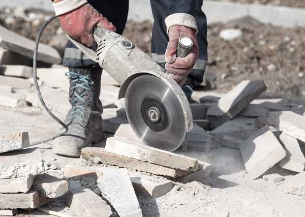 Mężczyzna tnący płytę przecinarką do betonu