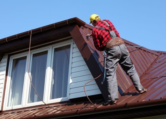 Mężczyzna malujący dach agregatem natryskowym